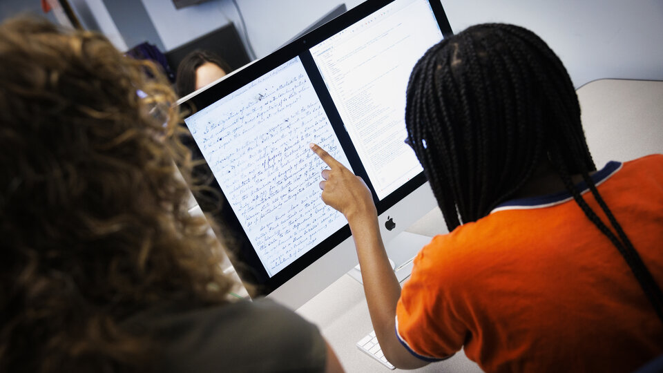 A student points to the legal text on a computer screen while a professor looks on.
